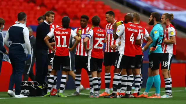 Exeter City manager Matt Taylor talks to his players during a drink break