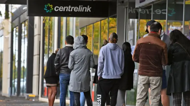 A queue of people wait outside a welfare office in March