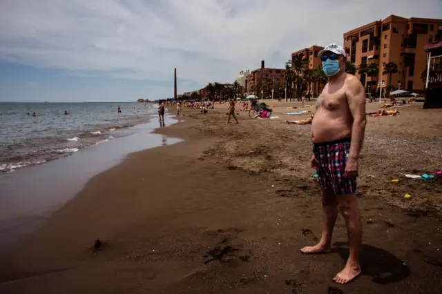 A man wearing a face mask on a beach in Malaga