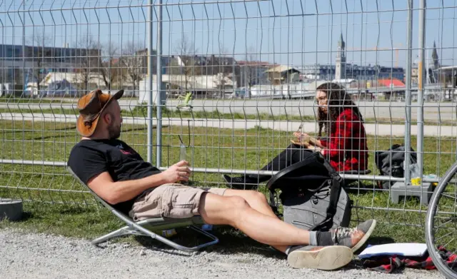 A man and a woman talk through fences set up by Swiss and German authorities on the German-Swiss border