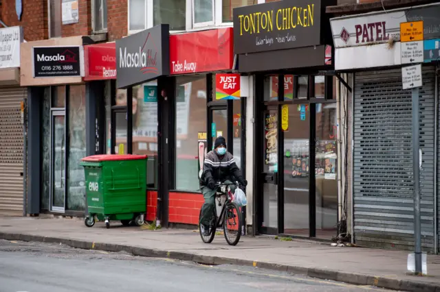 Man cycles past closed shops