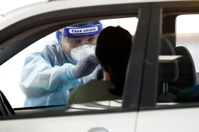 An official wearing a face shield conducts a test on a motorist in Melbourne