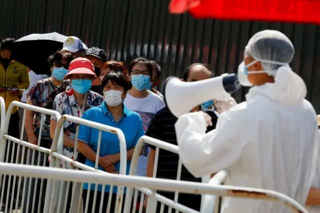 People line up to receive nucleic acid tests at a temporary testing site in Beijing