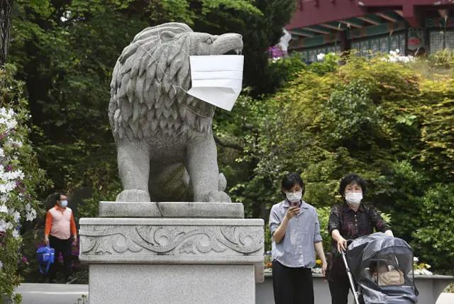 A face mask is put on a statue of a lion at a zoo in Seoul