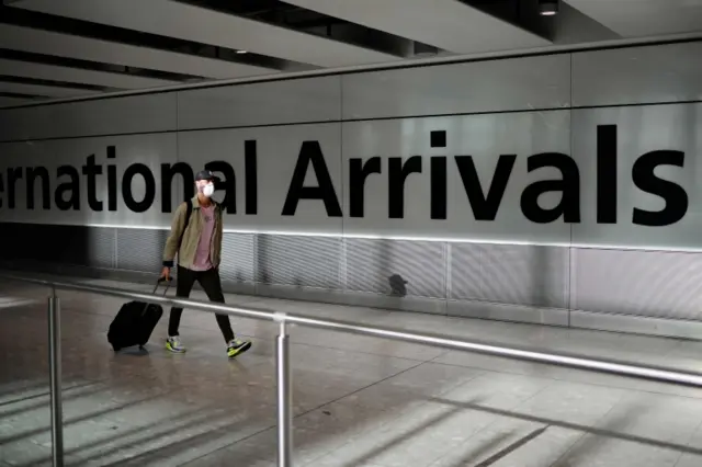 A traveller wears a mask at Heathrow Airport