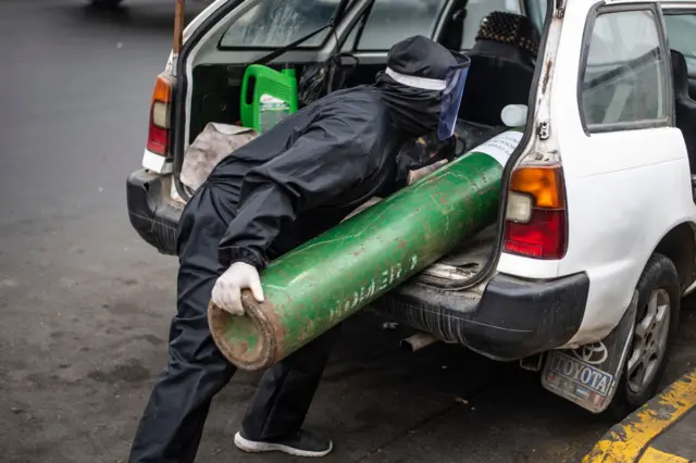 A man loads an empty oxygen cylinder into a taxi to refill it for a relative, outside the area of respiratory diseases of the 2 de Mayo Hospital in Lima on June 3, 2020