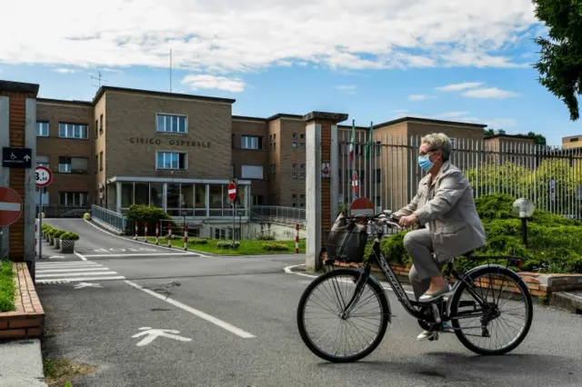 A resident rides her bicycle past the municipal hospital in Codogno, southeast of Milan