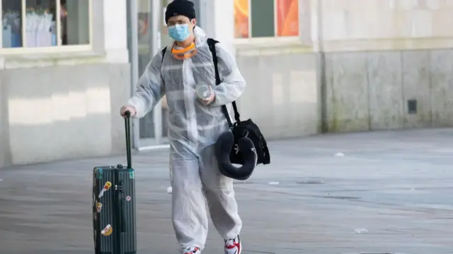 A passenger attends Cardiff Central Station with face mask and protective body suit