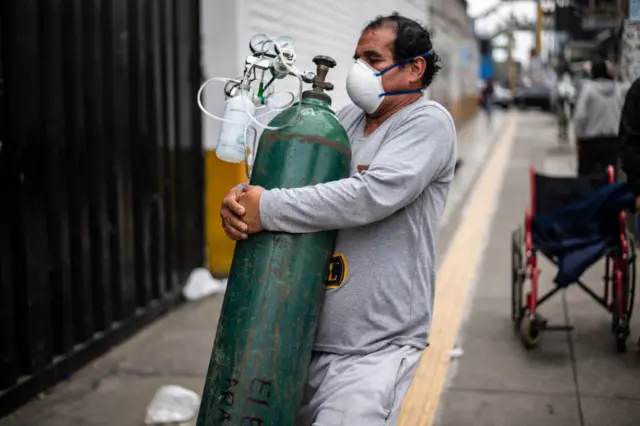 A man carries an oxygen cylinder to deliver it to a relative at the area of respiratory diseases of the 2 de Mayo Hospital in Lima on June 3, 2020