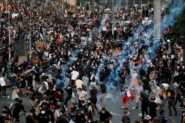 People run from tear gas as they attend a banned demonstration planned in memory of Adama Traore