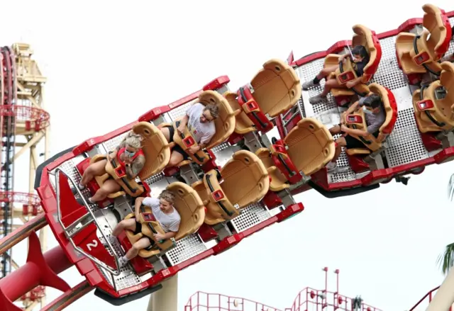 Visitors ride a roller coaster at Universal Studios theme park on the first day of reopening