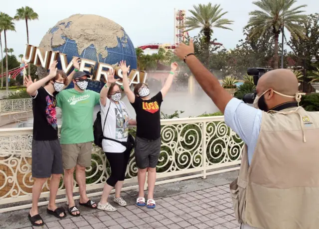 Visitors wearing a face mask pose for a photo at Universal Studios theme park