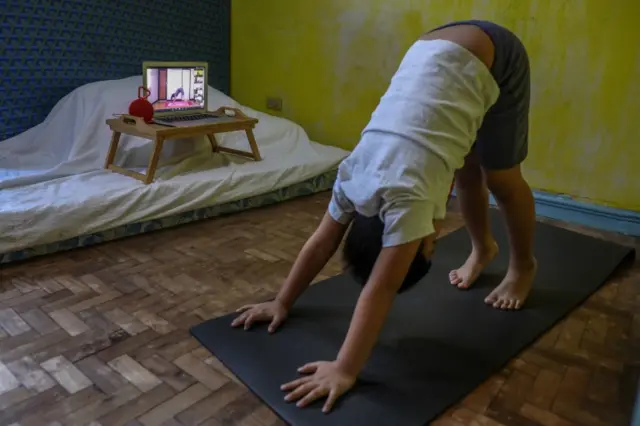 A boy performs a yoga pose during an online activity class in Makati, Philippines