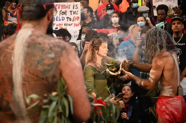 Aboriginal protesters perform a traditional smoking ceremony before the start of the rally in Sydney