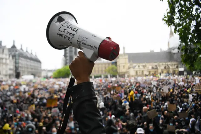 Protesters hold placards at a demonstration at Parliament Square in London, Britain, 6 June 2020