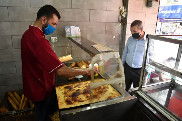 A sandwich shop worker serves a customer