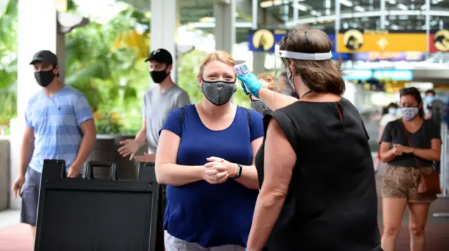 A Universal Studios employee takes the temperature of a guest during the first day of reopening from the coronavirus pandemic at Universal Orlando Resort on June 05, 2020 in Orlando, Florida