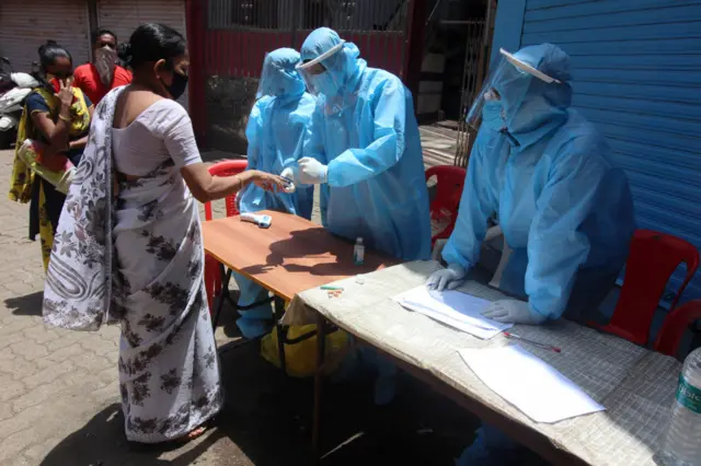 A healthcare worker measures the pulse of a woman in the Dharavi slum area of Mumbai, India on June 07, 2020.