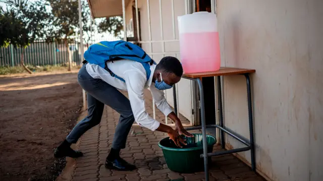 A pupil sanitises his hands before entering a classroom