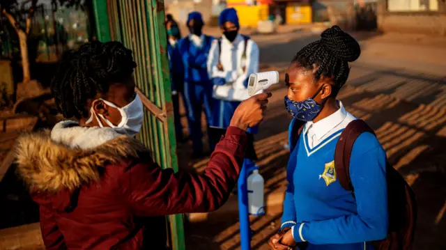 A pupil at the Winnie Mandela Secondary School has her temperature measured as she enters the school