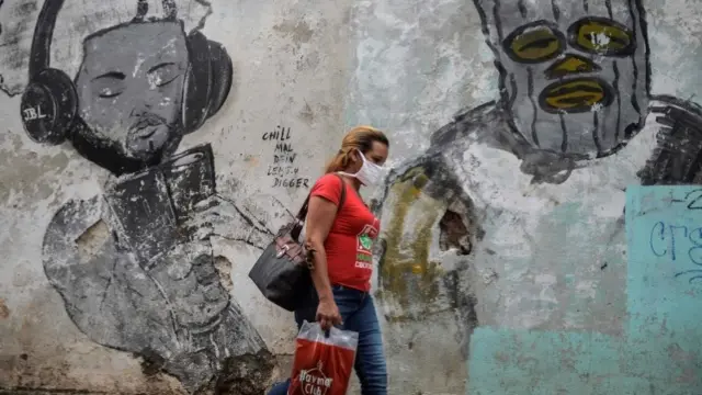 Woman wearing a face mask in front of mural