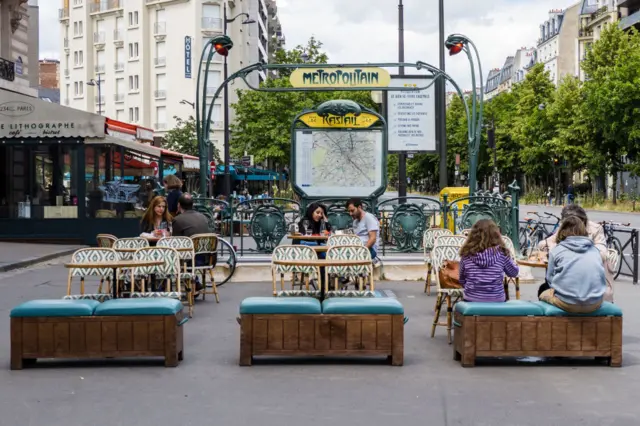 People sit outside cafes in Paris