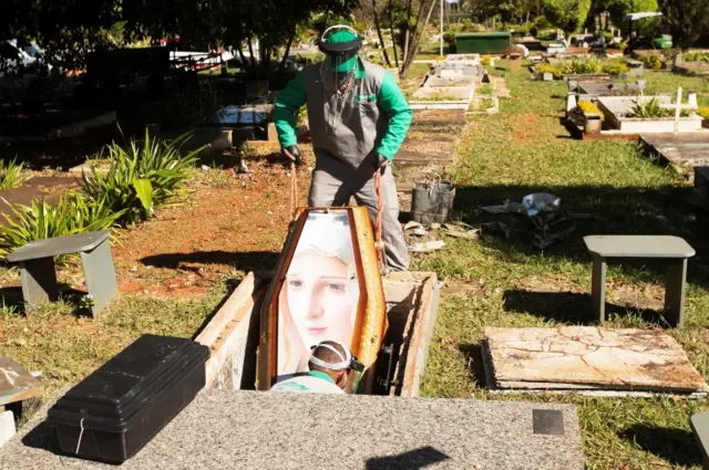 Workers at the Campo de Esperanza cemetery bury a coronavirus victim in Brasilia, Brazil