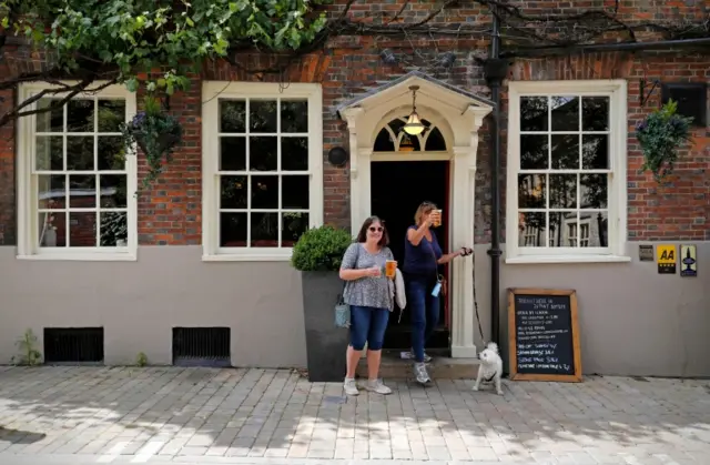 Women walk out of pub with takeaway beer