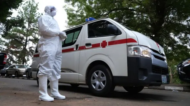 A health worker stands next to an ambulance in Abuja