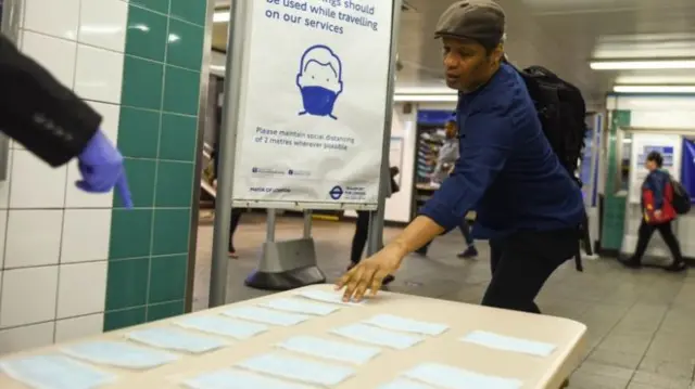 Man picking face coverings from table