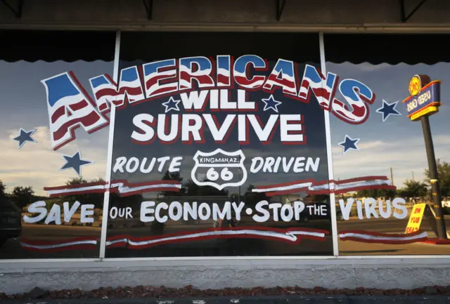 An automobile shop displays a sign reading in part 'Save Our Economy Stop The Virus' along historic Route 66 amid the coronavirus pandemic on May 24, 2020 in Kingman, Arizona