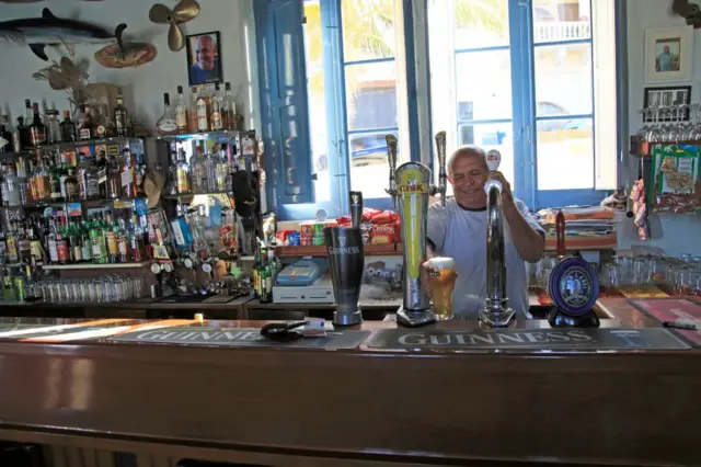 Barman pulling pints of beer Inside Gleneagles Bar pub at Mgarr, Gozo, Malta