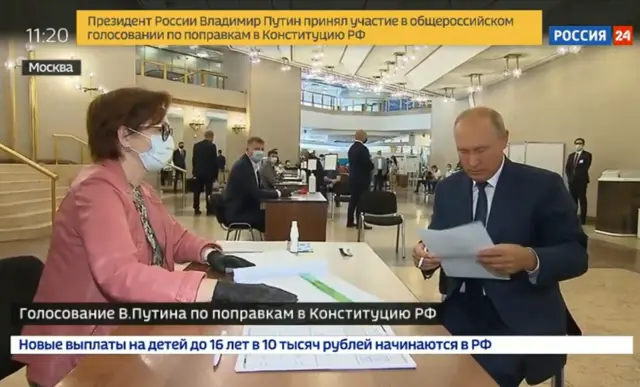 Vladimir Putin holds a ballot paper