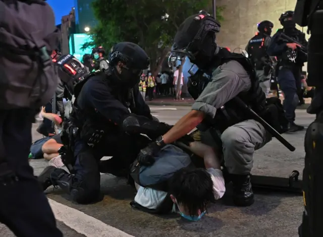 Police officers detain protesters during a rally