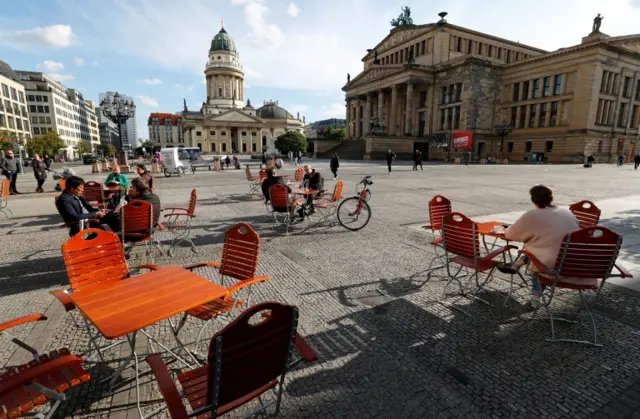 People enjoy the weather at a cafe at Gendarmenmarkt square in Berlin