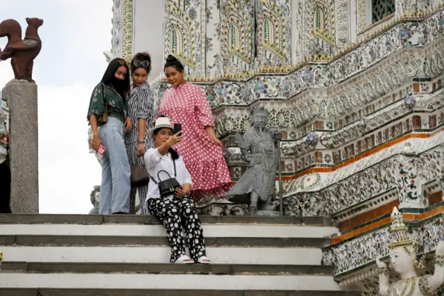 Tourists pose at the Wat Arun temple in Bangkok