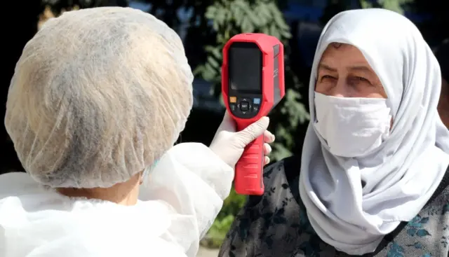 A woman's temperature is checked at a hospital in Sarajevo