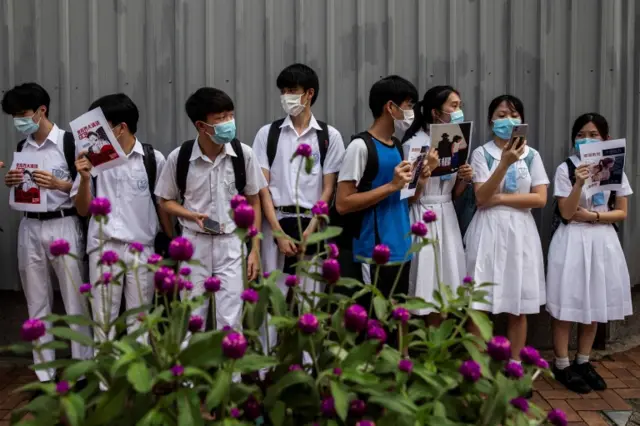 School students hold signs during a pro-democracy protests near their school in Hong Kong on June 12, 2020