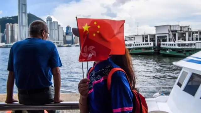 A member of a local community group holds Chinese and Hong Kong flags as she disembarks from a boat in Victoria Harbour on the 23rd anniversary of the city's handover from Britain in Hong Kong on July 1, 2020