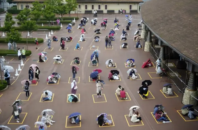 Visitors practice social distancing as they wait to enter Tokyo DisneySea in Urayasu