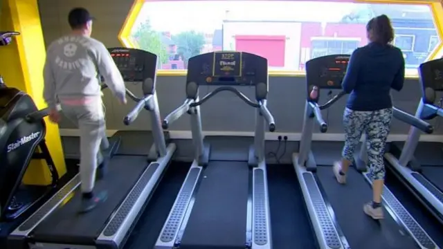 Two people running on treadmills with one turned off between them