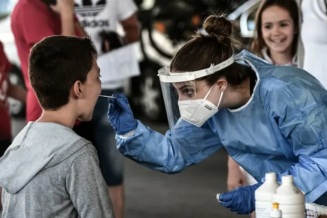 A public health worker collects a swab sample from a boy to test for coronavirus