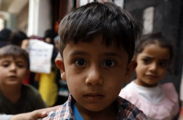 Yemeni children wait to get free food rations from a charity group in Sanaa, Yemen