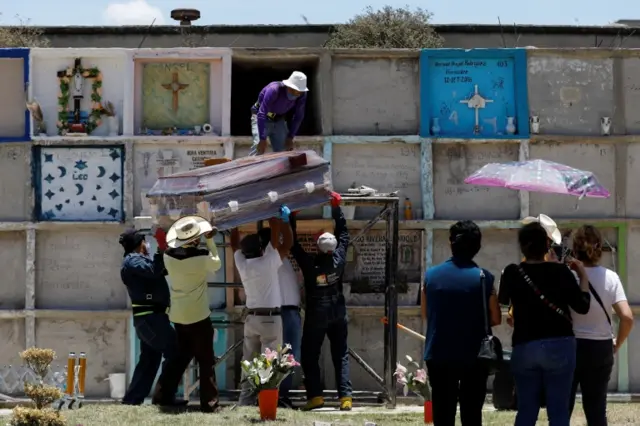 Funeral workers carry the coffin of a woman, who died of the coronavirus disease (COVID-19) to put it inside a niche, as the family say their last goodbyes at the Municipal cemetery in Nezahualcoyotl, State of Mexico, Mexico June 12, 2020