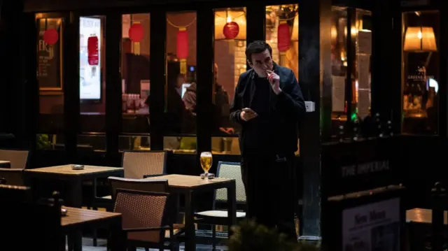 A man smoking outside a pub in London