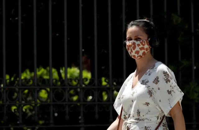 A woman wearing a face mask walks along a street in Barcelona