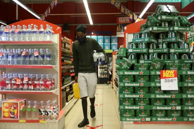 A man wearing a protective face mask buys alcohol at a liquor store as South Africa