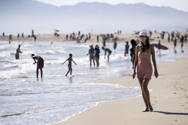 A woman wearing a face mask walks at Venice Beach during a heatwave amid the coronavirus pandemic