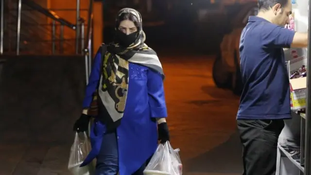 A woman wears face mask at night in Tehran, Iran (12 July 2020)