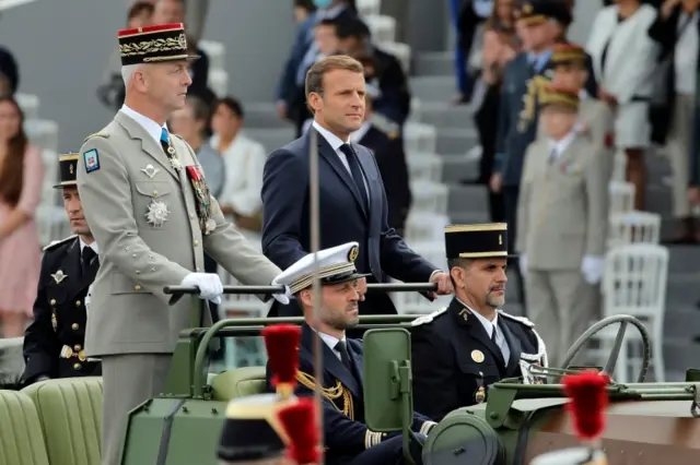 French President Emmanuel Macron (R) and Chief of the Defence Staff General Francois Lecointre, stand in the command car as they review troops prior to the annual Bastille Day military ceremony